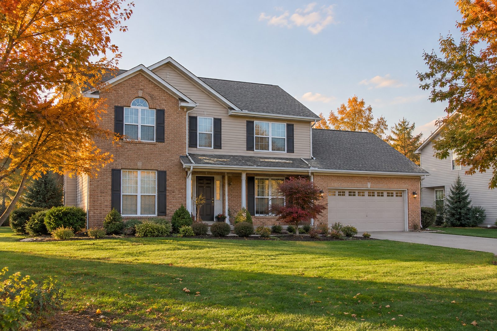 Two-story brick home with autumn maple trees in Fort Wayne, Indiana